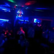 A vibrant nightclub scene in Kigali, Rwanda, with people dancing under colorful lights.