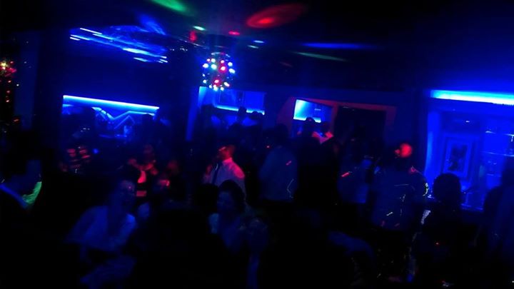 A vibrant nightclub scene in Kigali, Rwanda, with people dancing under colorful lights.